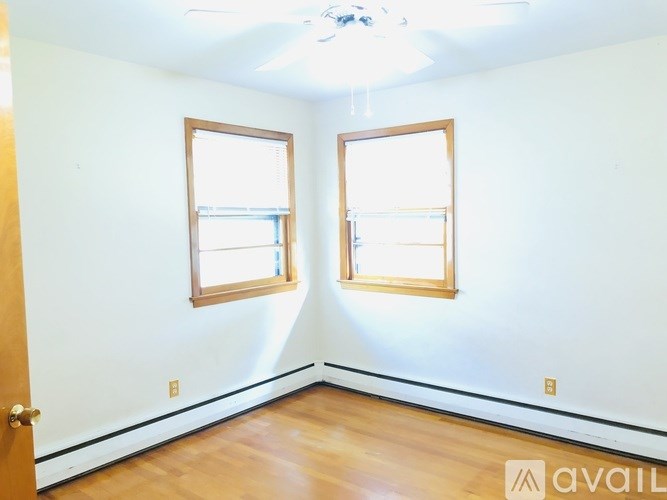 A room with two windows and a door is available for rent.