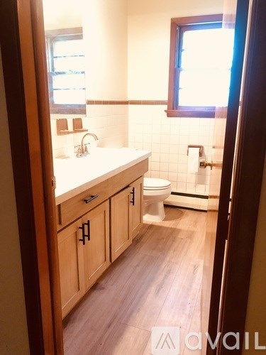 A bathroom with a toilet, sink, and wooden cabinets.