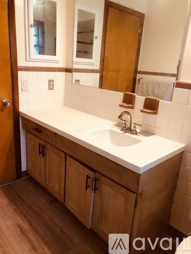 A bathroom with a white sink and wooden cabinets.
