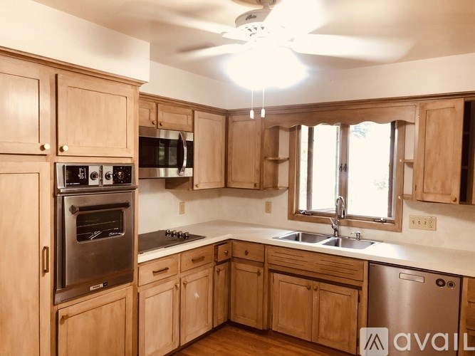 A kitchen with wooden cabinets and a stainless steel dishwasher.