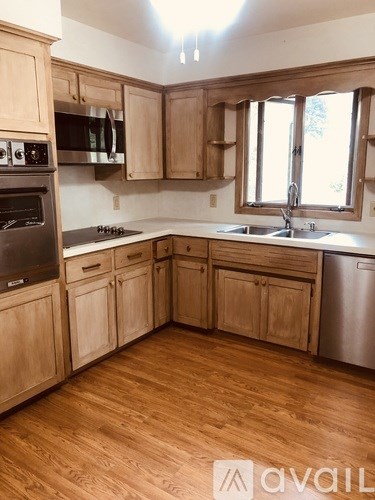 A kitchen with wooden cabinets and a stainless steel refrigerator.