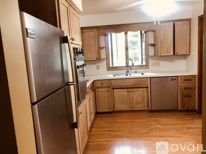 A kitchen with wooden cabinets and a stainless steel refrigerator.