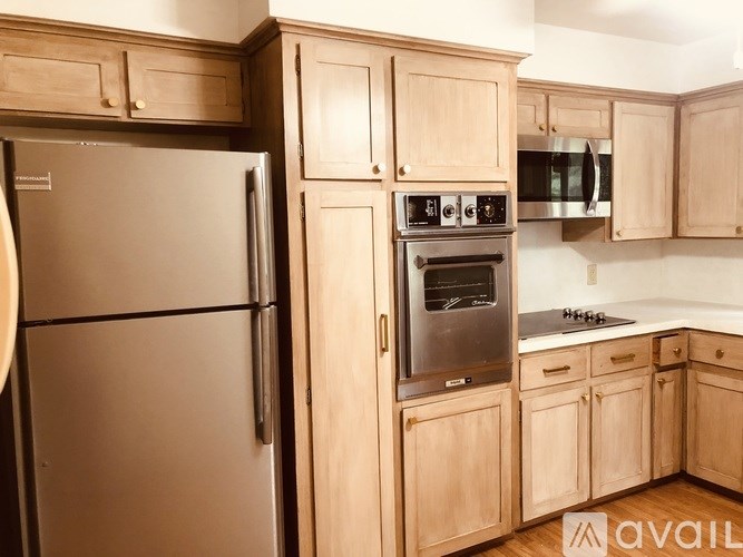 A kitchen with wooden cabinets and a stainless steel refrigerator.