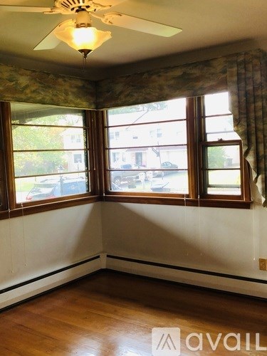 A room with a ceiling fan and two windows.