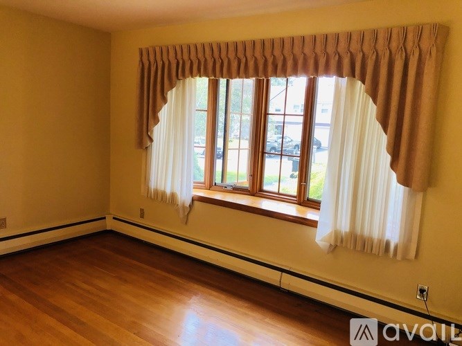 A room with a window covered by a brown and white curtain.