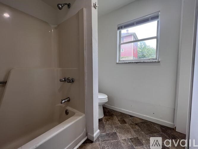 A bathroom with a tub, toilet and window.