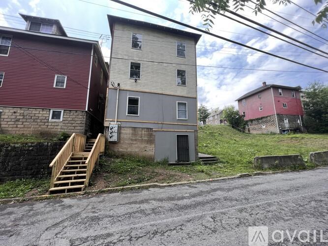 A red building with a grey building next to it and a small staircase leading to the grey building.