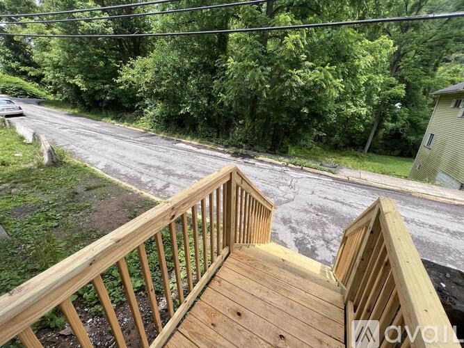 A wooden deck overlooks a wet road with a car parked on the side.