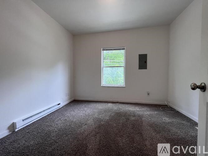 A room with a carpeted floor, a window, and a door.