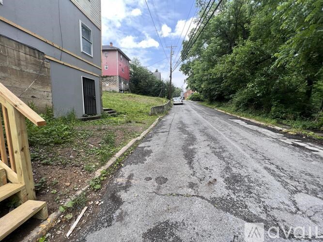 A road with a wooden fence on the left side and a red building in the background.