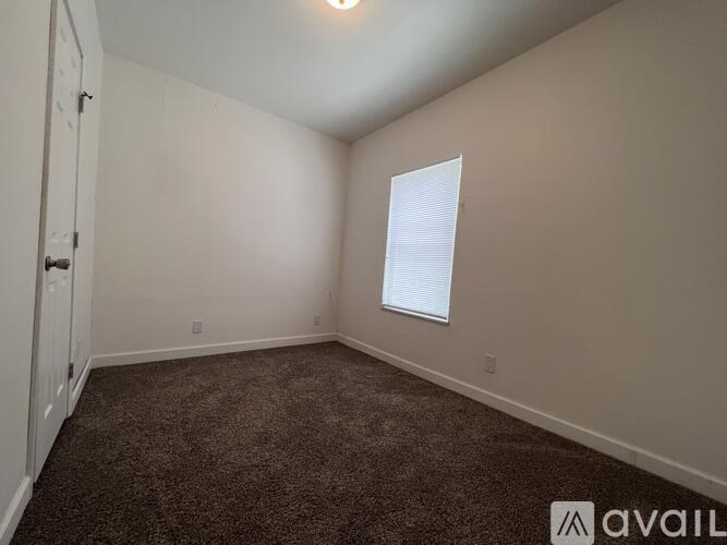 A room with a carpeted floor and a window with blinds.