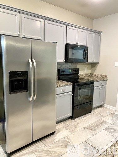 A kitchen with a stainless steel refrigerator and black oven.