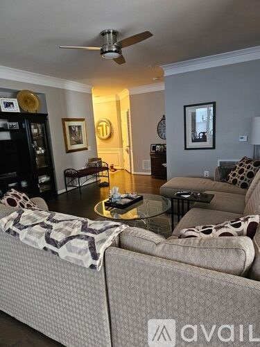 A living room with a grey couch and a glass coffee table.