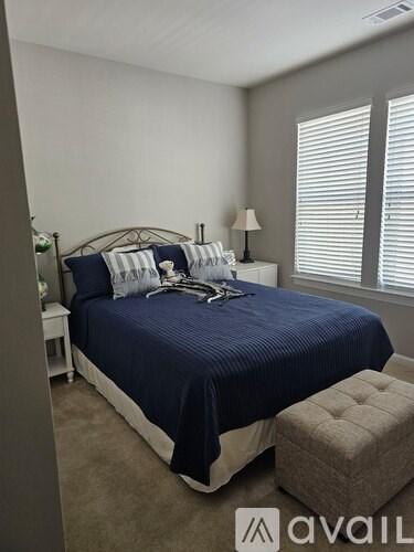 A bedroom with a bed, nightstand, lamp, and window with blinds.