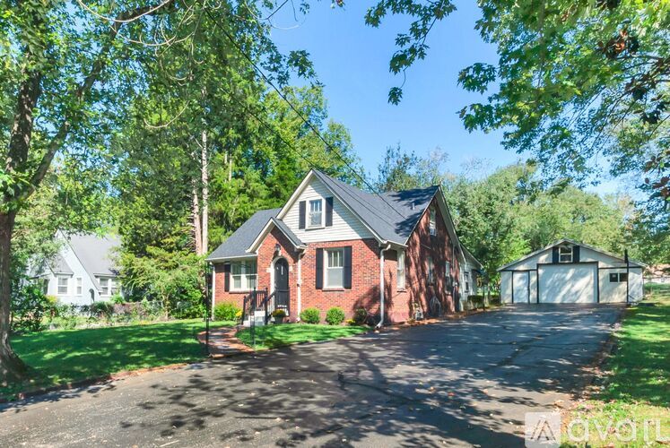 A house with a driveway and trees in the background.
