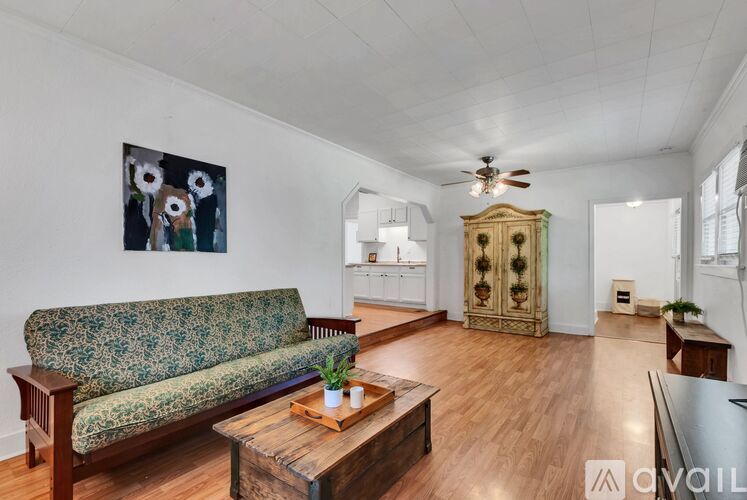 A living room with a green floral sofa, a wooden coffee table, and a painting on the wall.
