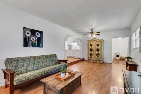 A living room with a green floral sofa, a wooden coffee table, and a painting on the wall.