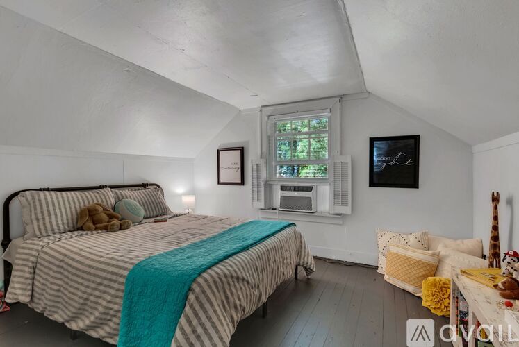 A bedroom with a bed, a chair, and a window.