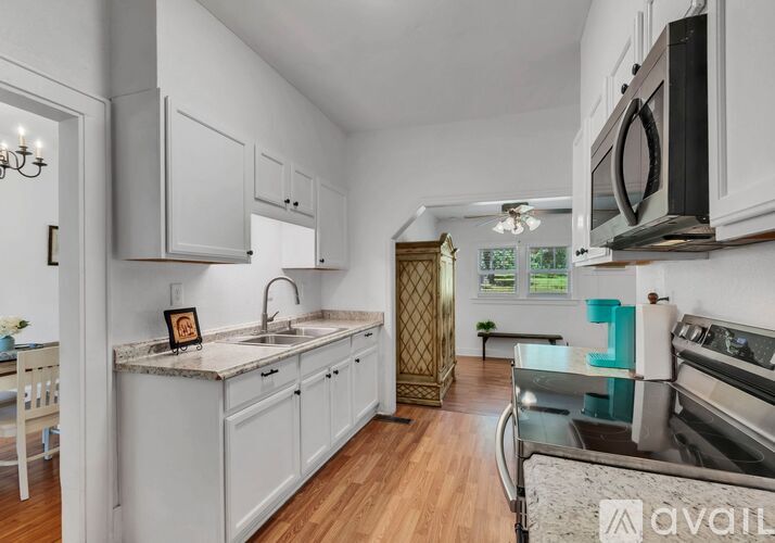A kitchen with white cabinets and a wooden floor.