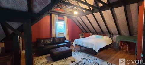 A bedroom with a bed, couch, and chair in it.