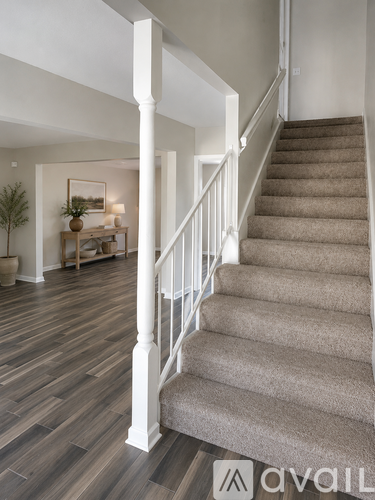 A spacious room with wood flooring and white walls.