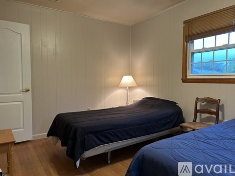 A bedroom with a bed, a chair, and a window.