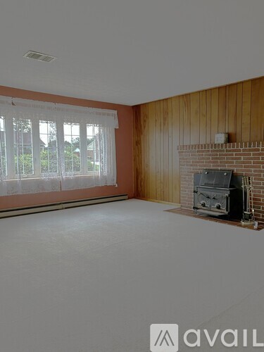 A living room with a fireplace and a window with blinds.