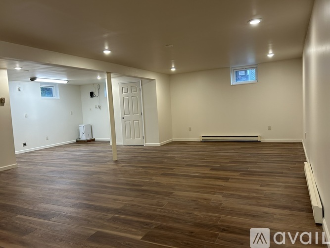 A spacious room with wooden flooring and white walls.