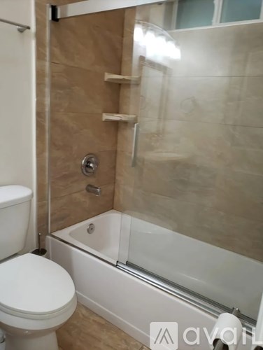 A white toilet sits next to a white bathtub in a bathroom.