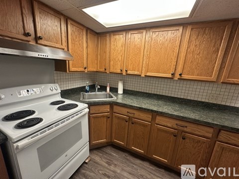 A kitchen with wooden cabinets and a white stove top oven.