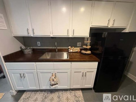 A kitchen with white cabinets and a black refrigerator.