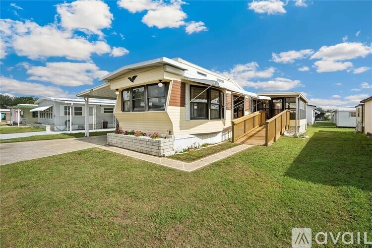 A mobile home with a brown deck and a white fence.