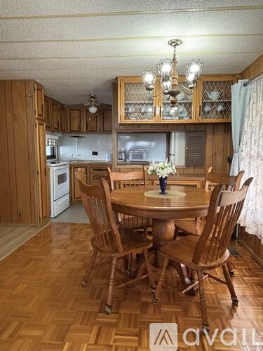 A wooden dining table with chairs and a chandelier in a kitchen.