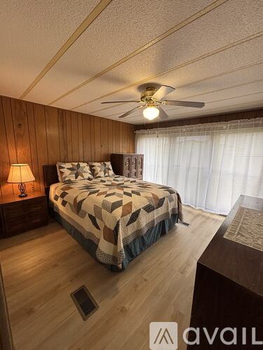 A bedroom with a bed, a ceiling fan, and a lamp.