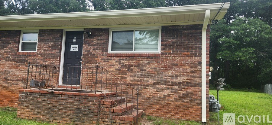 A brick house with a black door and a window with white blinds.