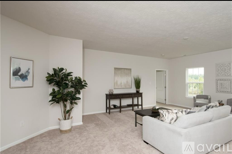 A living room with a white couch and a painting on the wall.