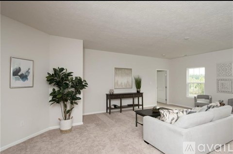 A living room with a white couch and a painting on the wall.