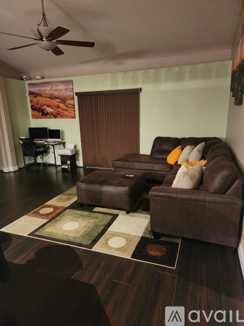 A living room with a brown couch and a rug.