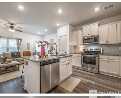 A kitchen with white cabinets and a wooden floor.