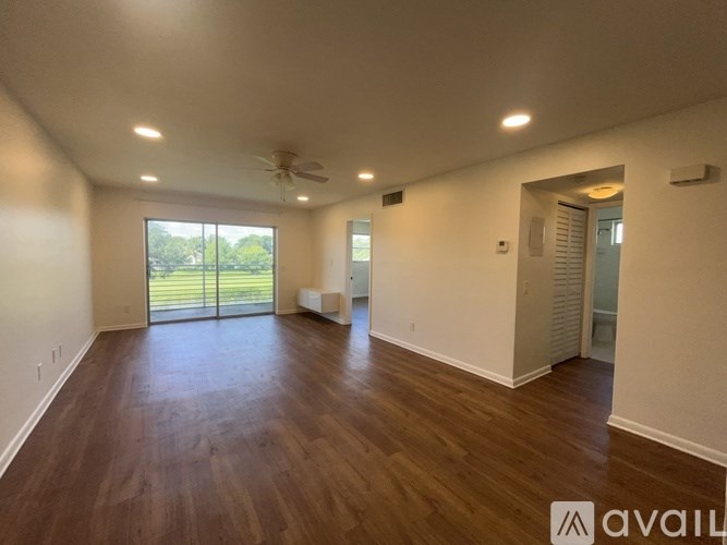 A spacious room with wooden floors and a ceiling fan.