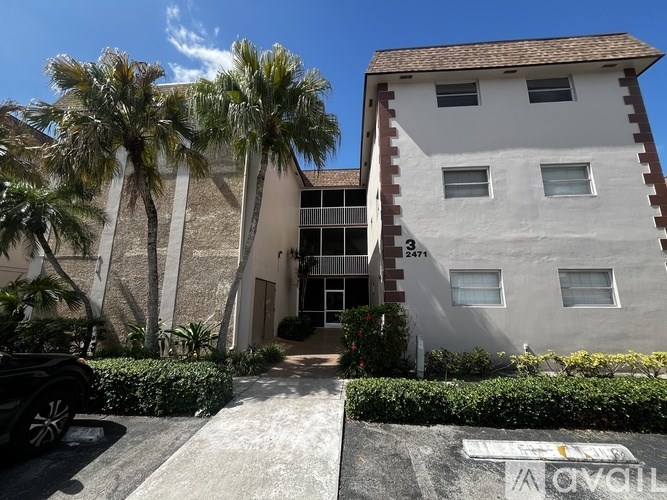 A white building with a red roof and a black car parked in front.