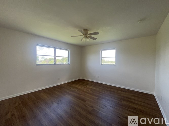 A room with wooden floors and two windows.
