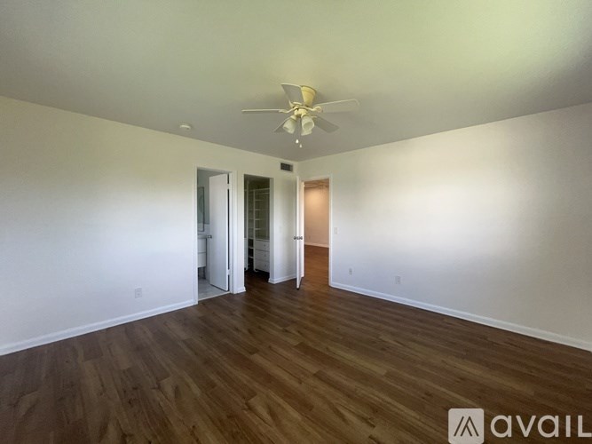 A room with a ceiling fan and wooden flooring.