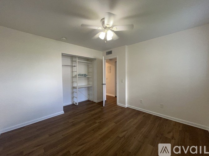 A room with a ceiling fan and wooden flooring.