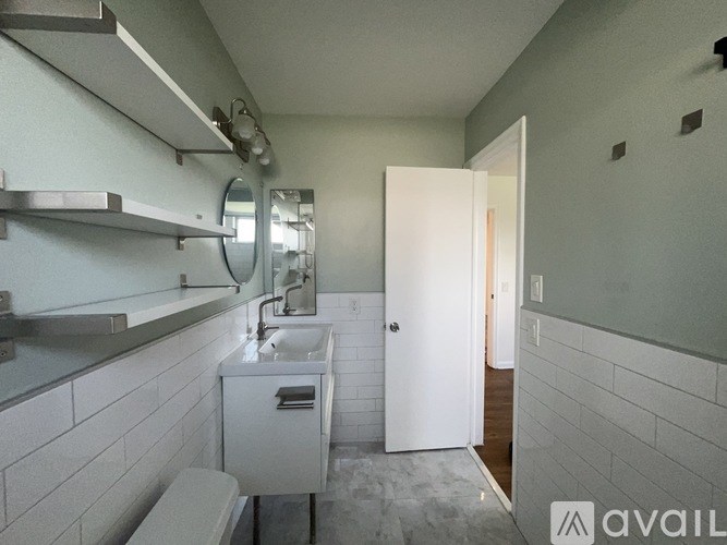 A bathroom with a toilet, sink, mirror, and a white door.