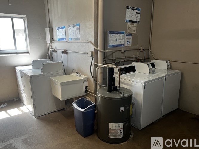 A room with a window, a sink, a toilet, and a trash can.