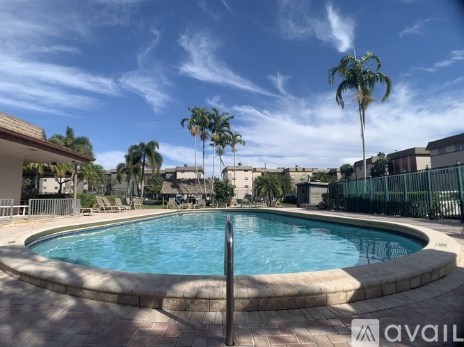 A pool surrounded by palm trees and a fence.