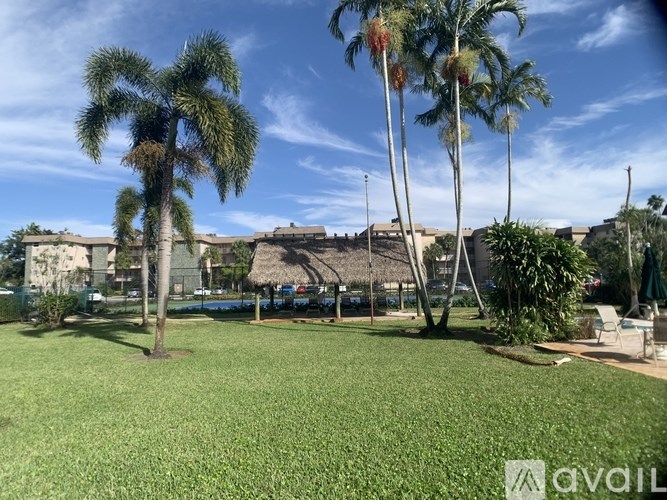 A grassy area with palm trees and a building in the background.