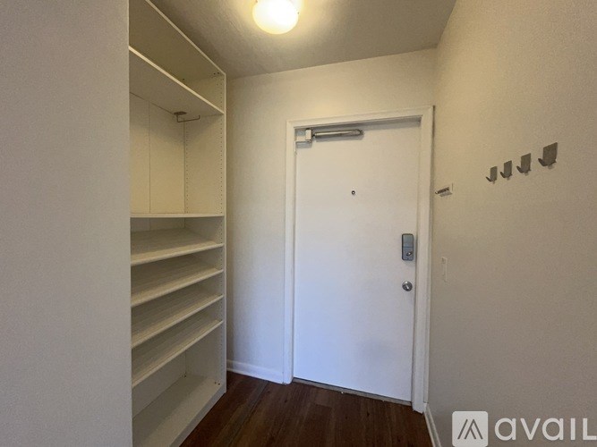 A white door with a silver handle is in a room with white walls and a wooden floor.