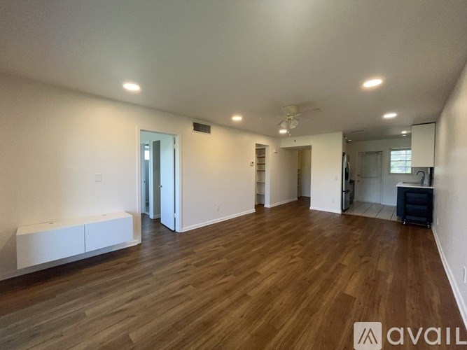 A spacious room with wooden flooring and white walls.